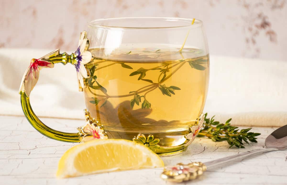 Tea in a glass mug, with thyme sprigs in it.