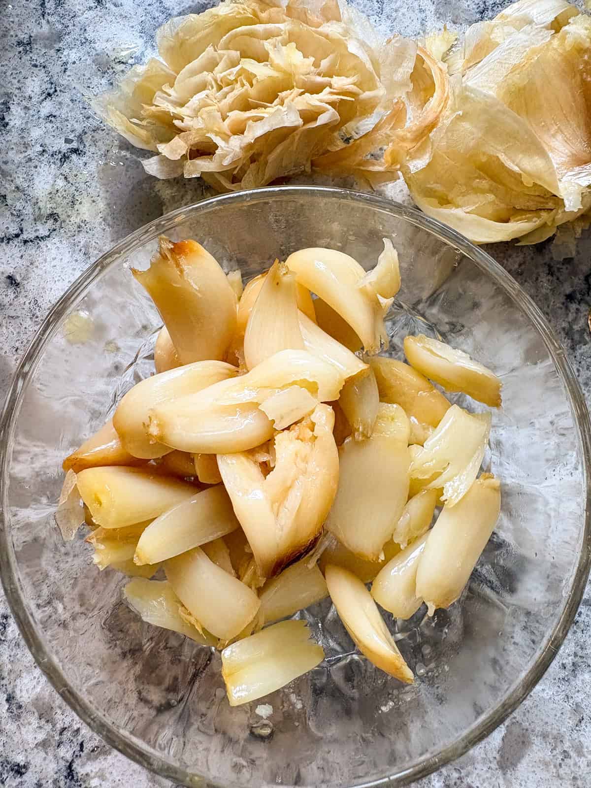 Roasted garlic cloves removed from the head, in a small glass bowl.