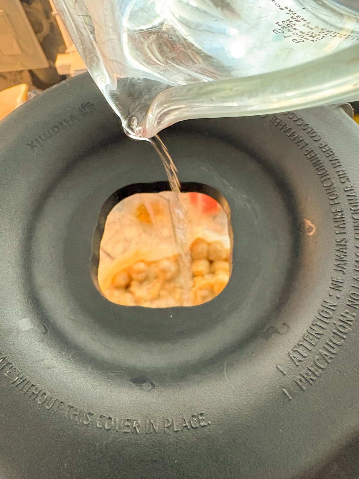 Water being poured into the top of the blender.