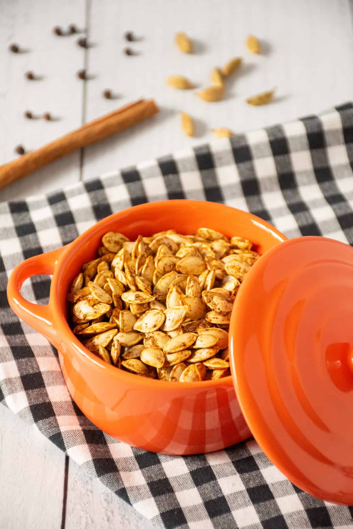 Roasted pumpkin seeds in a tiny orange crock.