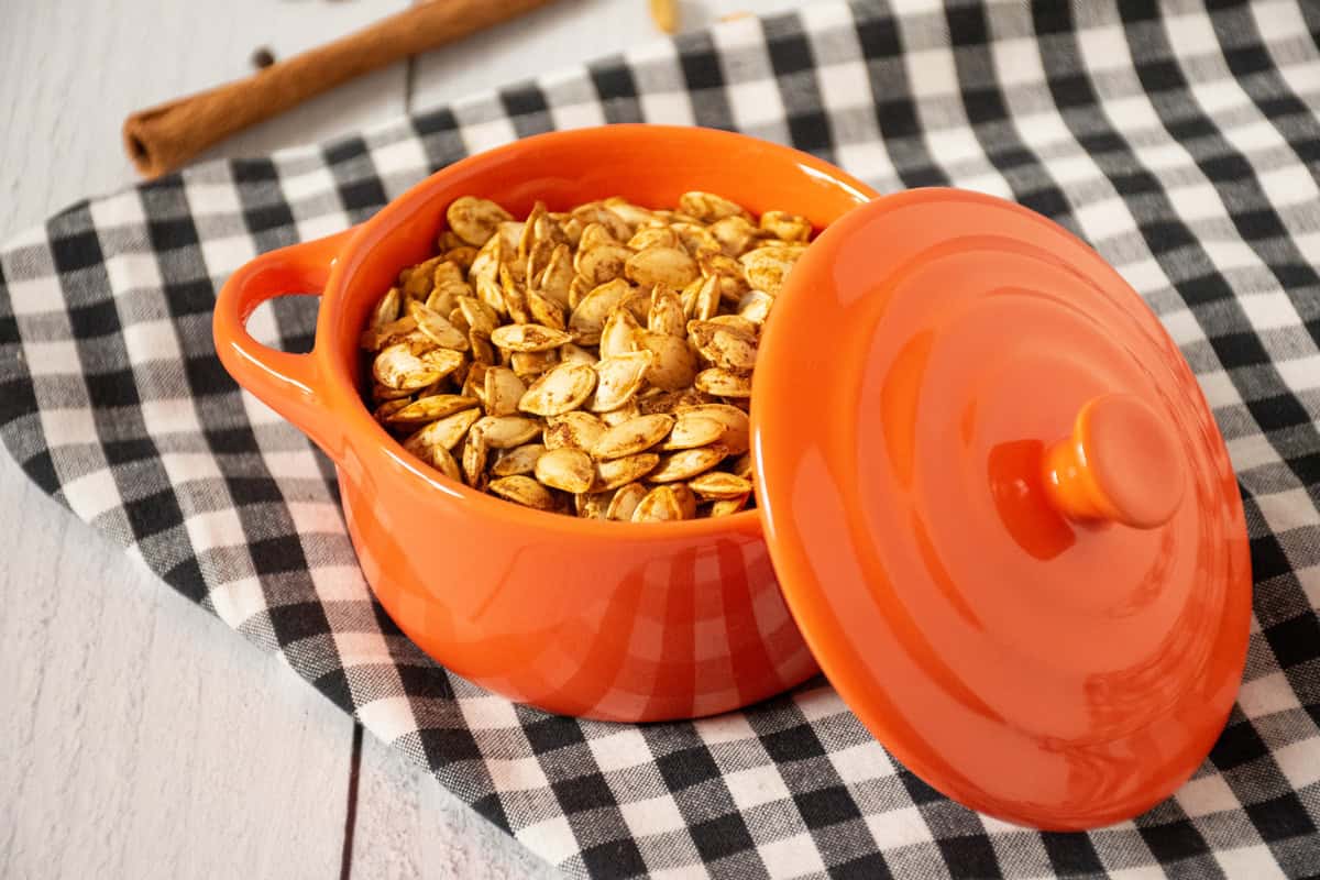 Roasted pumpkin seeds in a tiny orange crock.