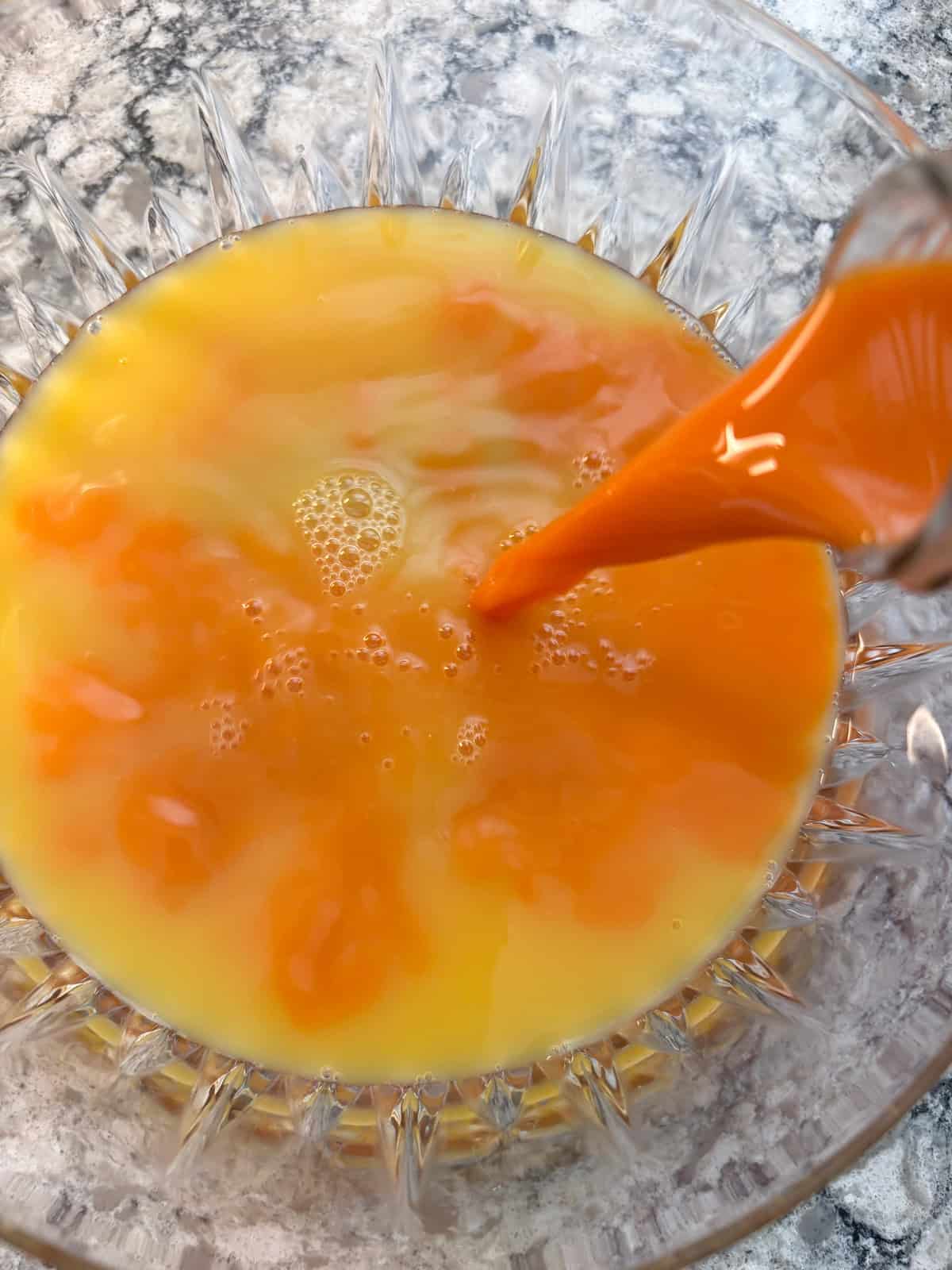 Orange juice and carrot juice being combined.