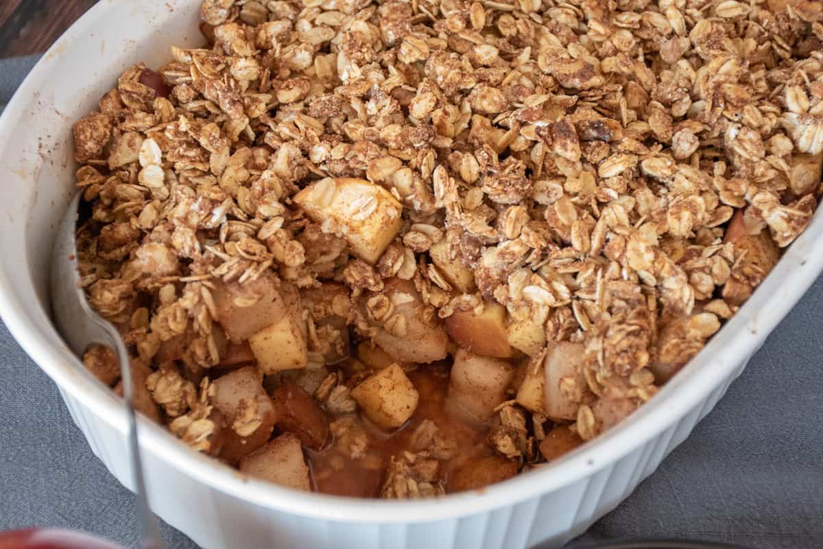 Apple pear crisp, in a baking dish, with a scoop removed to view inside.