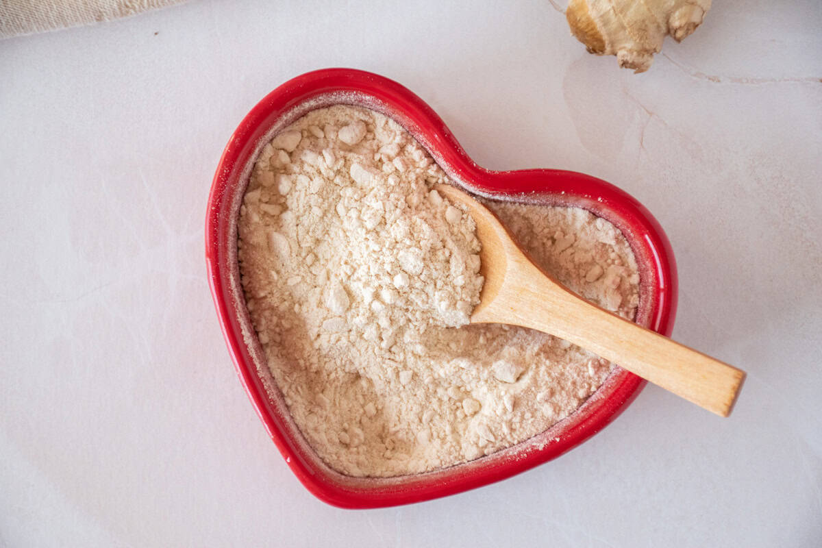 Seasoning powder made from pears and ginger, in a red heart shaped dish with a small wooden spoon.