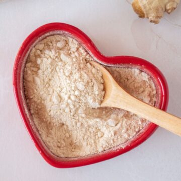 Seasoning powder made from pears and ginger, in a red heart shaped dish with a small wooden spoon.