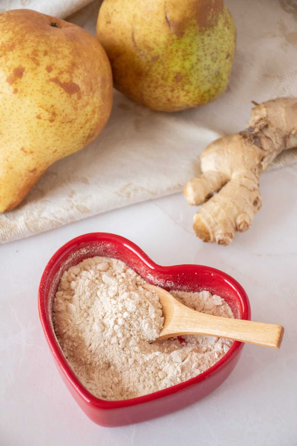Seasoning powder made from pears and ginger, in a red heart shaped dish with a small wooden spoon.