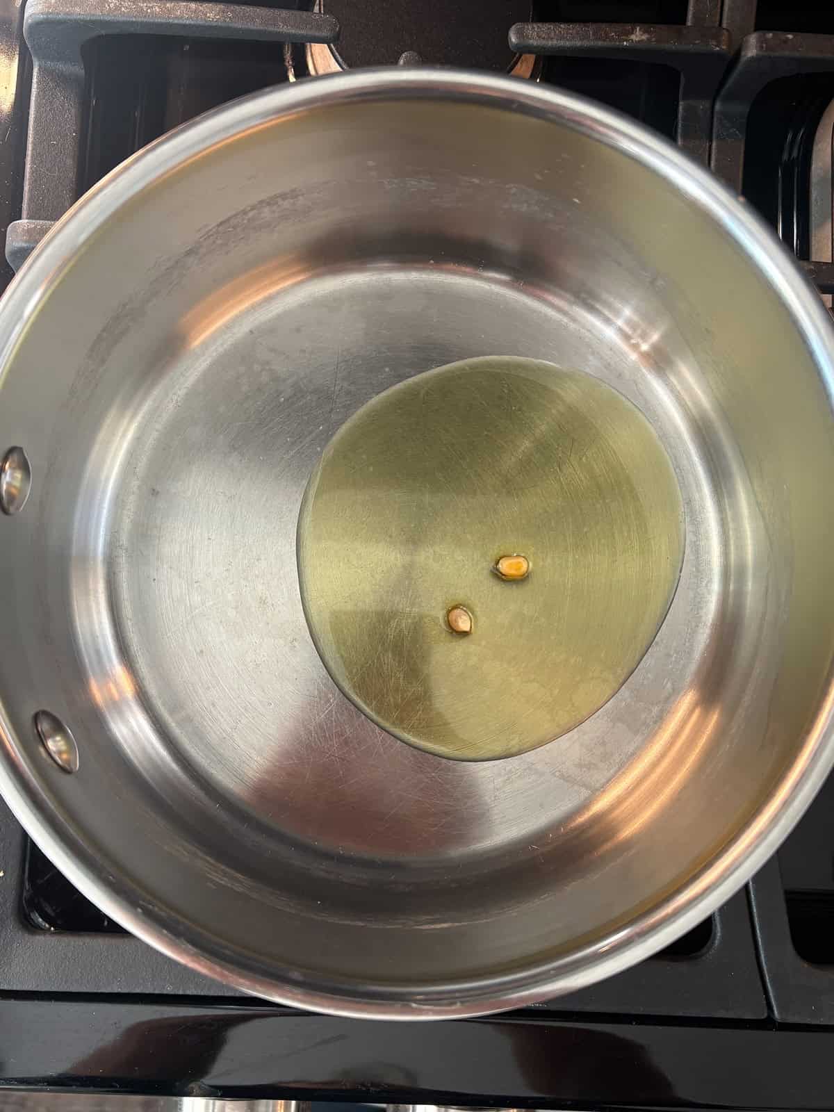 Oil in a pot, with 2 kernels of popcorn in it.