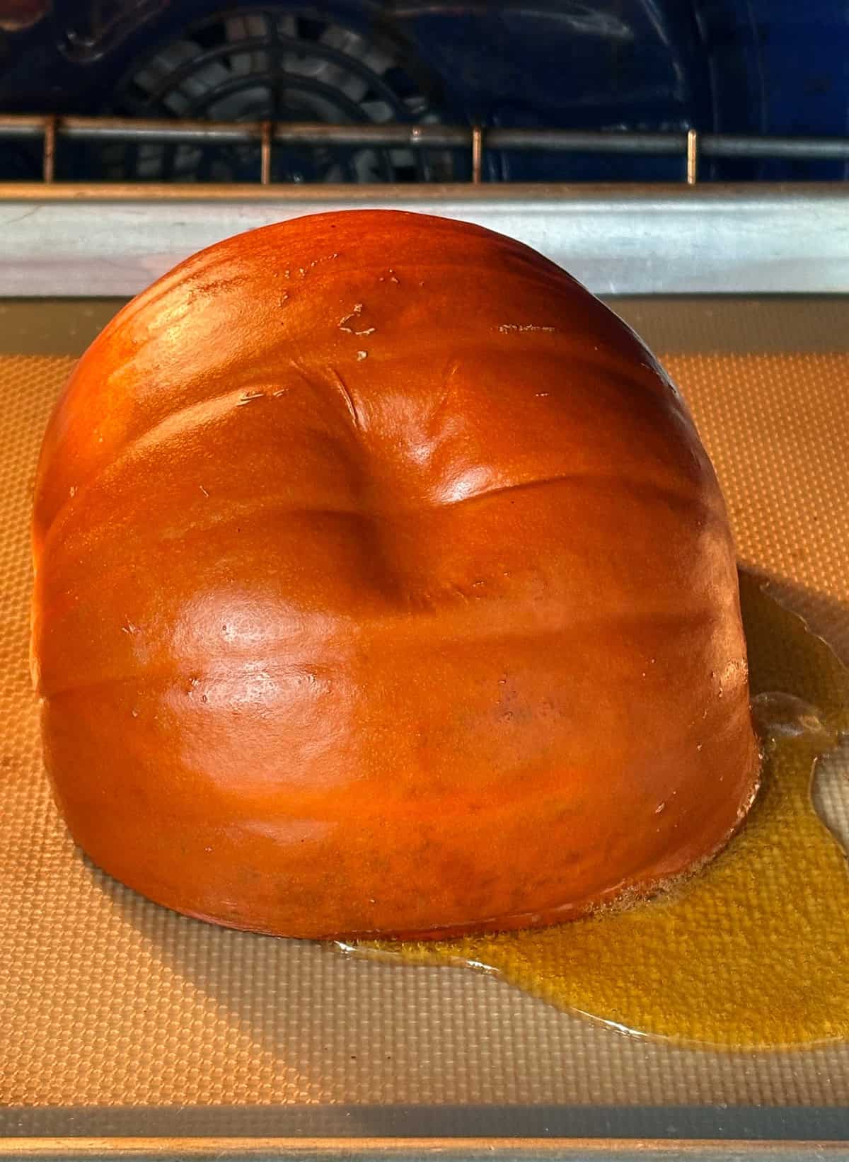 Face down pumpkin half, in the oven, with an indentation in the side, proving it is soft enough.