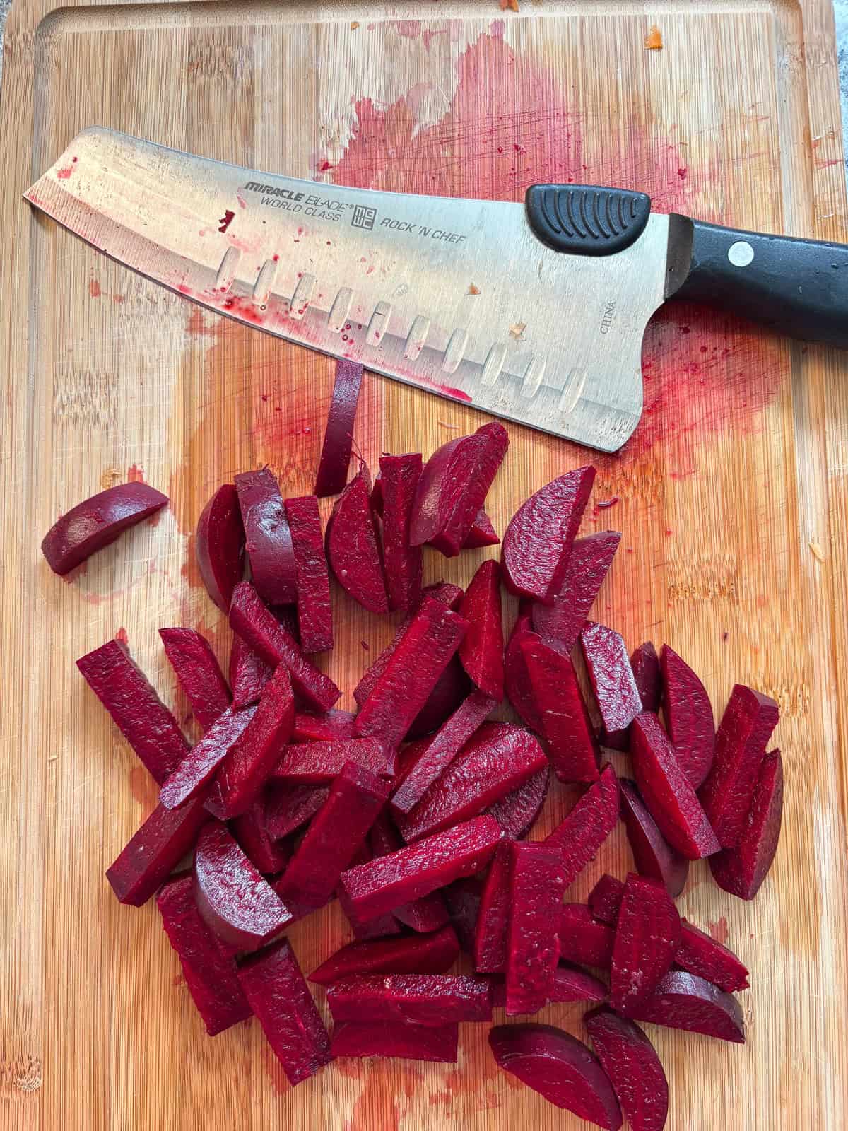 Beets, cut into large matchsticks, on a cutting board.