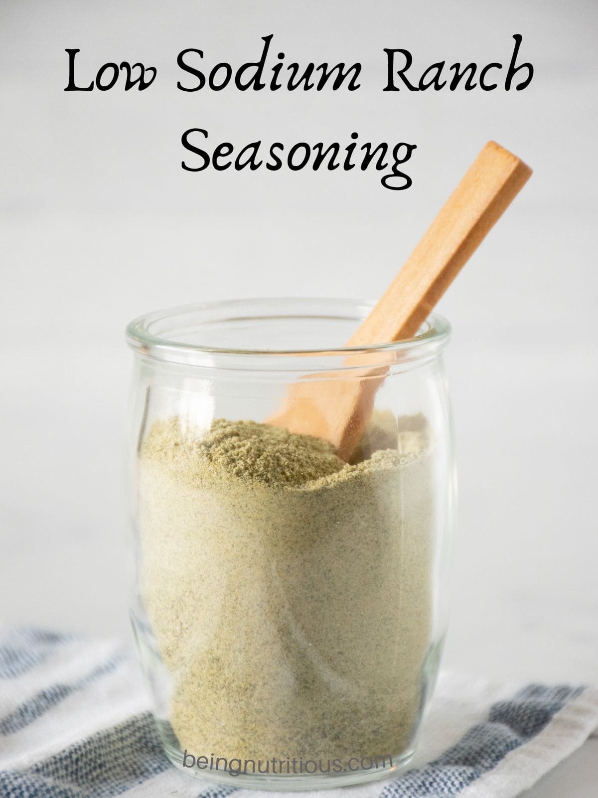 Small glass jar of ranch seasoning with a small wooden spoon in it. Text overlay: Low sodium ranch seasoning.
