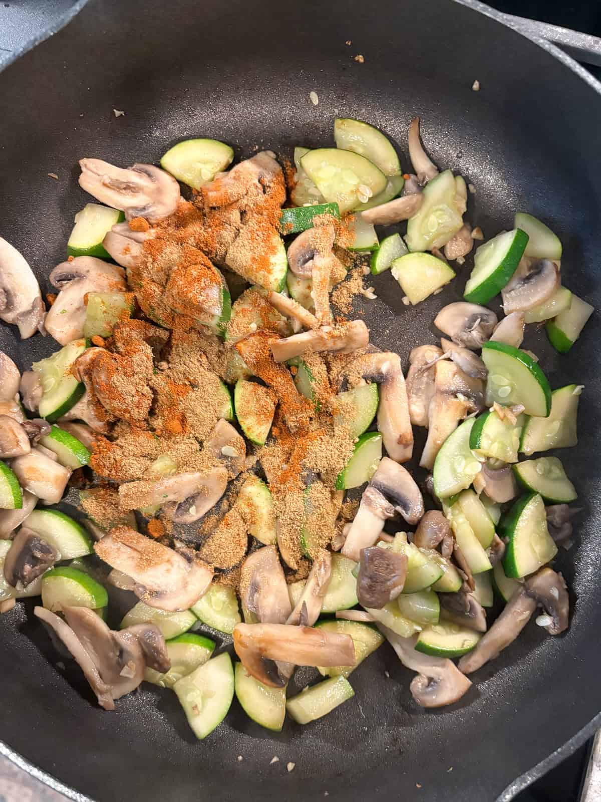 Spices sprinkled on to sautéing veggies.