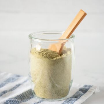 Small glass jar of ranch seasoning with a small wooden spoon in it.