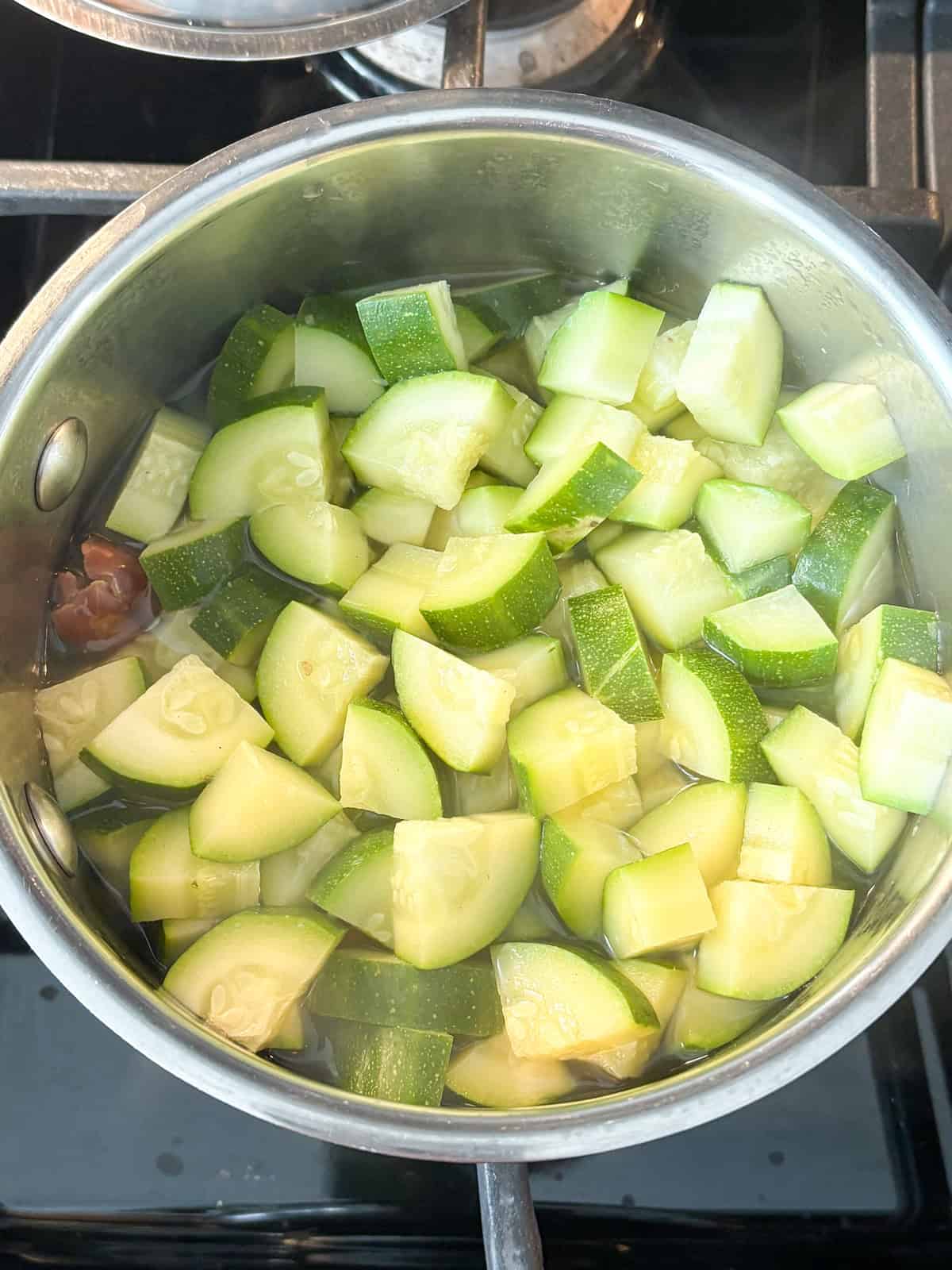 Zucchini and dates simmering in a small pot.
