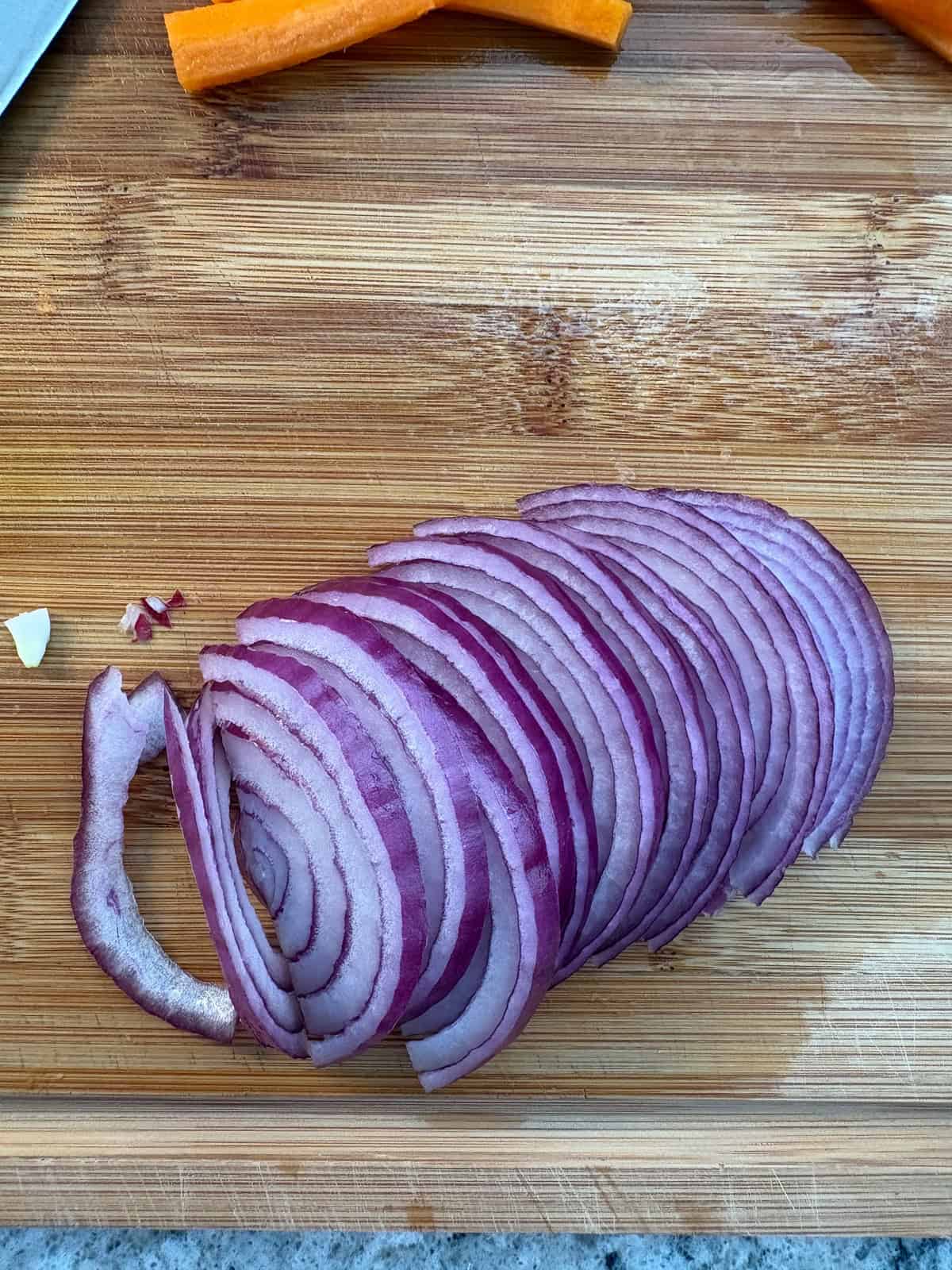 Sliced red onions on a cutting board.