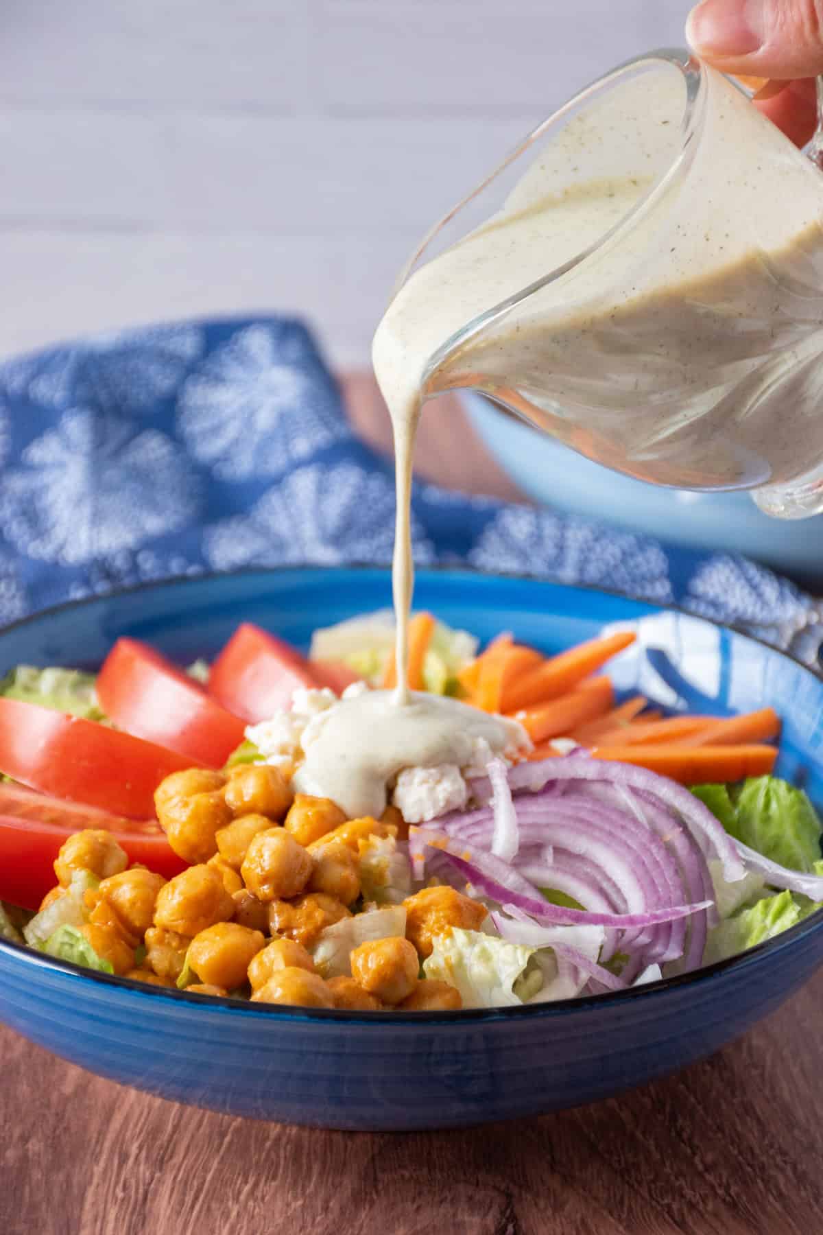 Salad with ranch dressing being poured on.