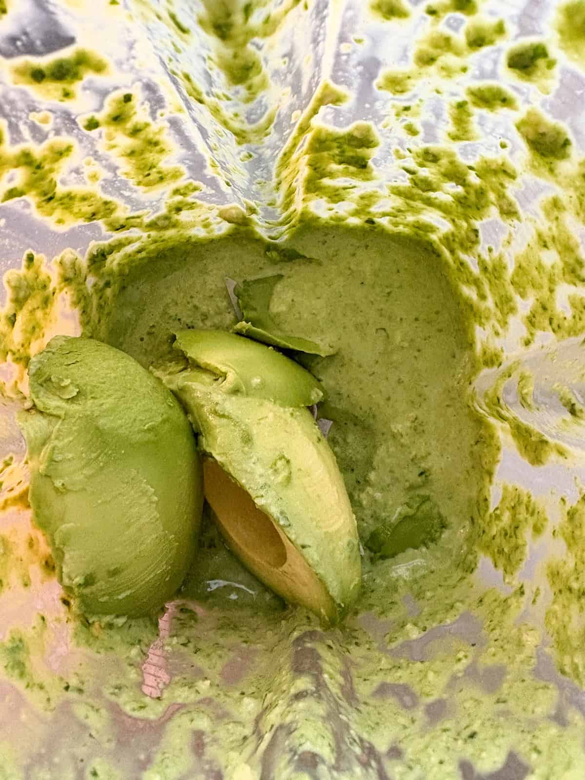 Avocado added to the spinach mixture in a blender.