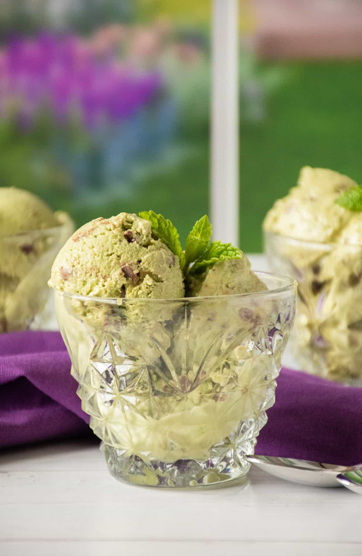 Cup of mint chip ice cream, garnished with fresh mint leaves.