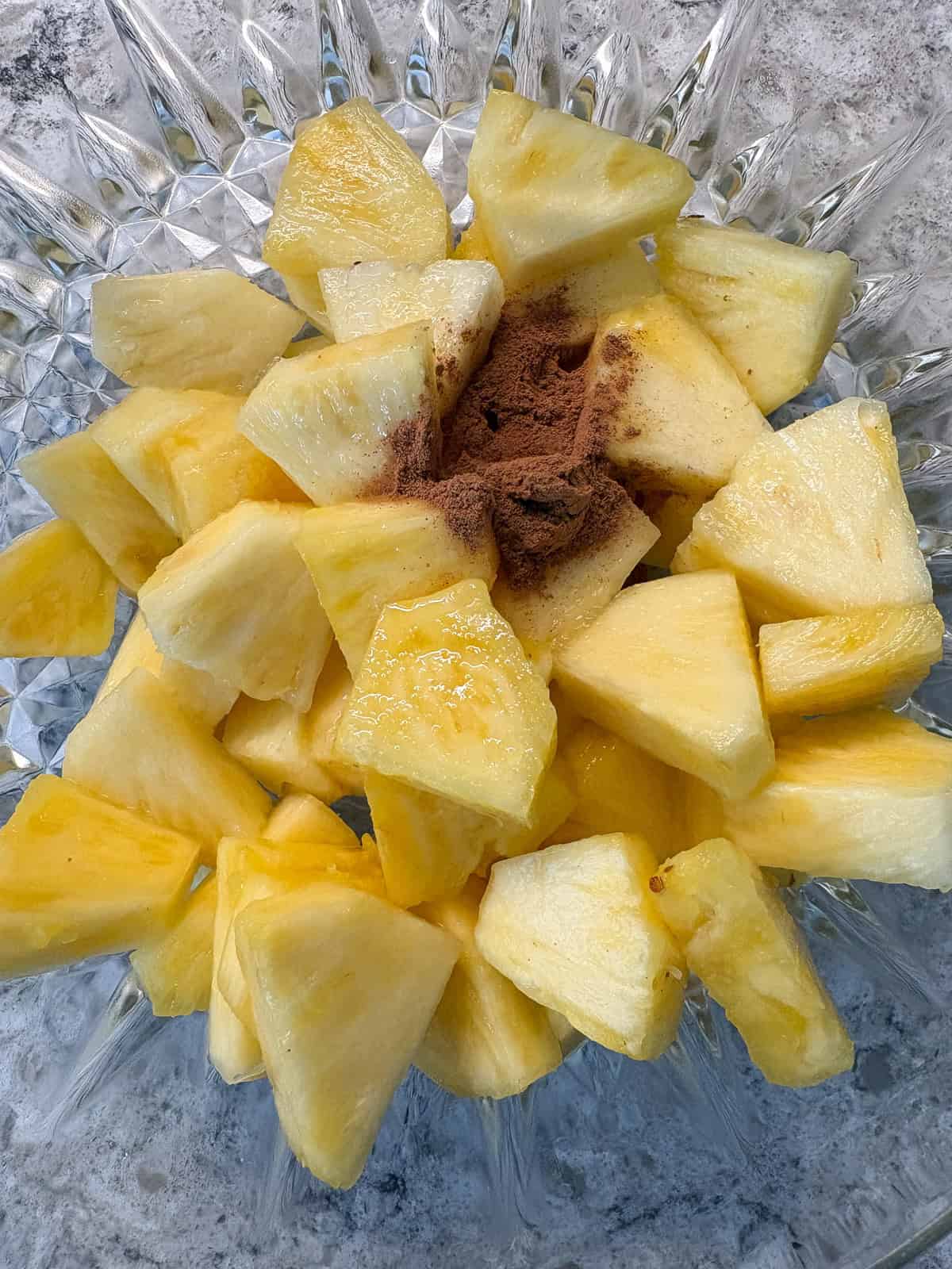 Pineapple pieces in a bowl, with lime juice and cinnamon added.
