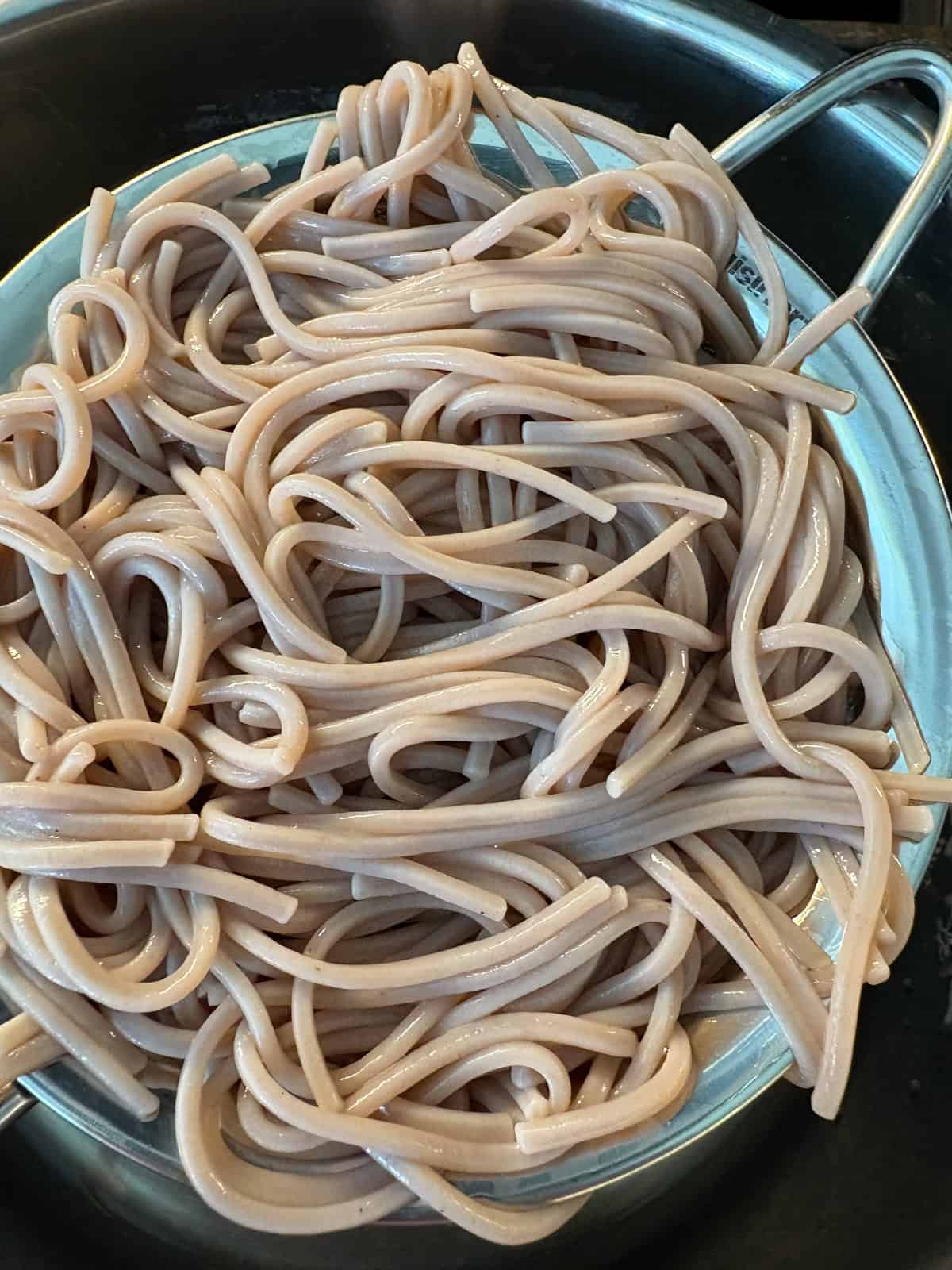 Cooked, drained, and rinsed soba noodles in a strainer.