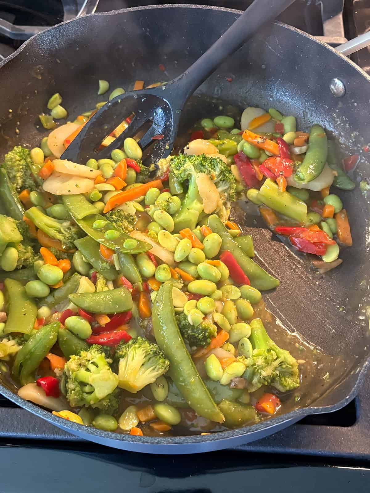 Stir fry veggies in thickened sauce, in a skillet.