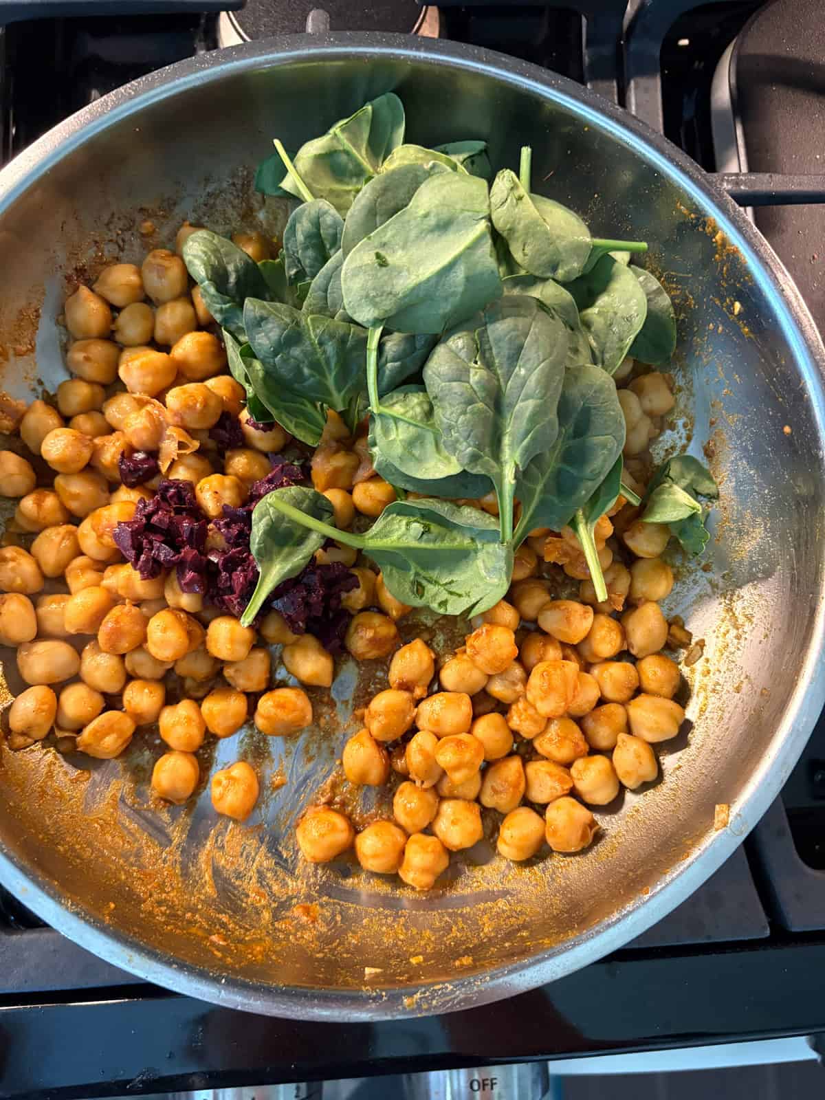 Spinach and minced olives added to sauteing chickpeas.