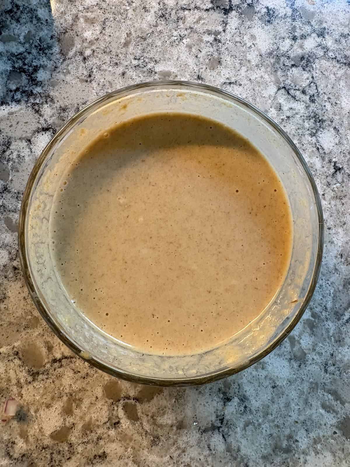 Tahini dressing, mixed, in a glass bowl.