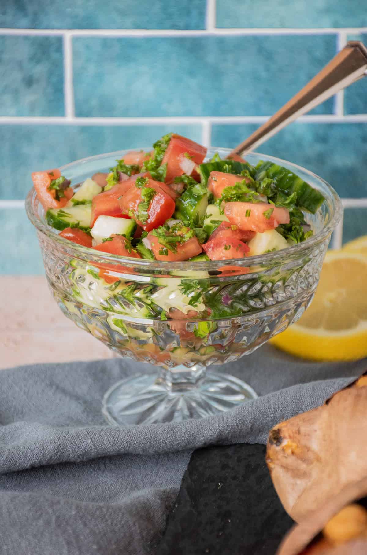 Cucumber salad in a glass bowl with a spoon.