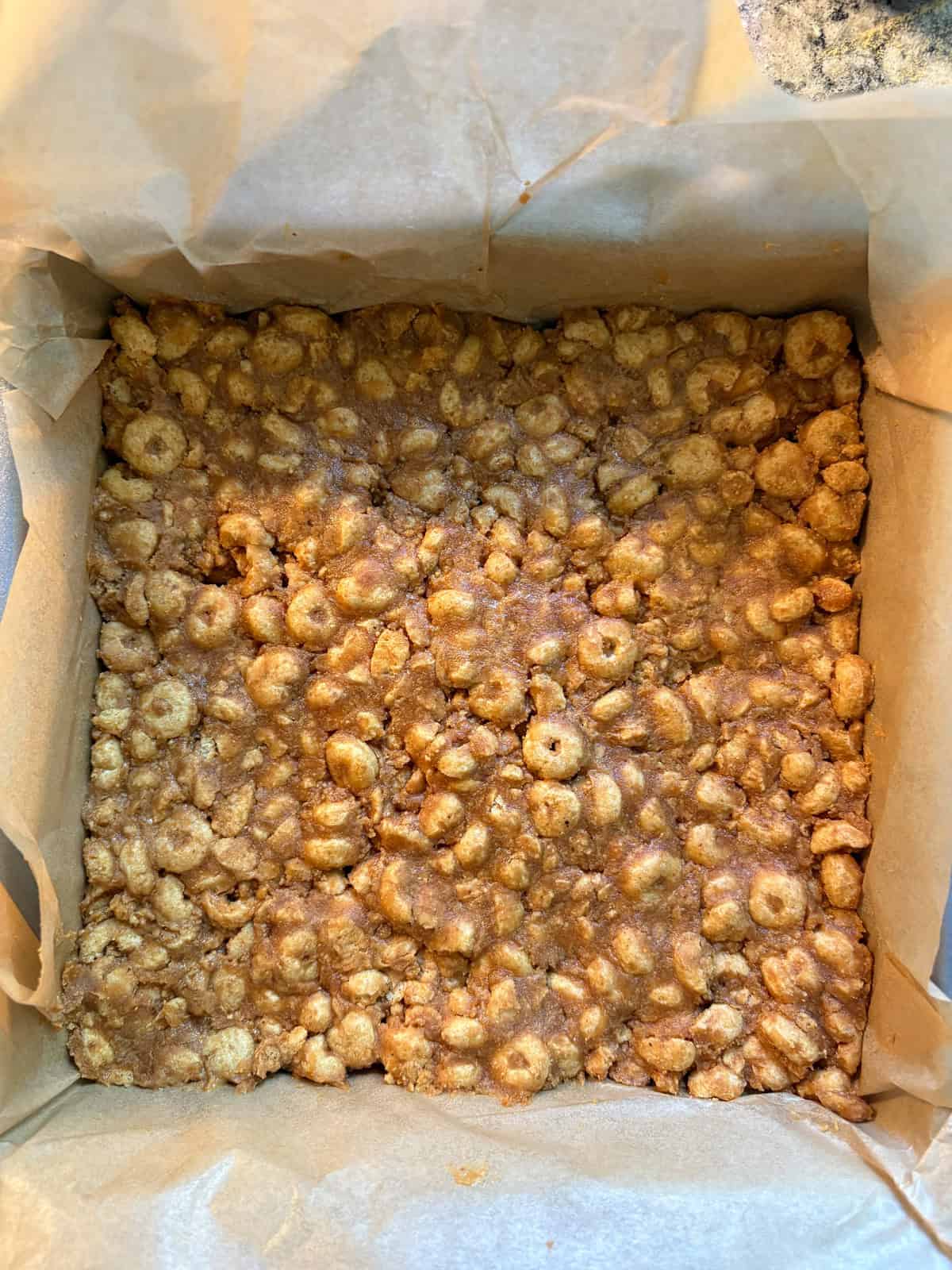 Cereal peanut butter mixture pressed into a pan.