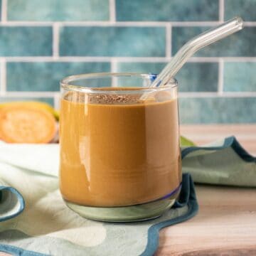 Chocolate smoothie in a glass, with a clear straw, sprinkled with chia seeds.