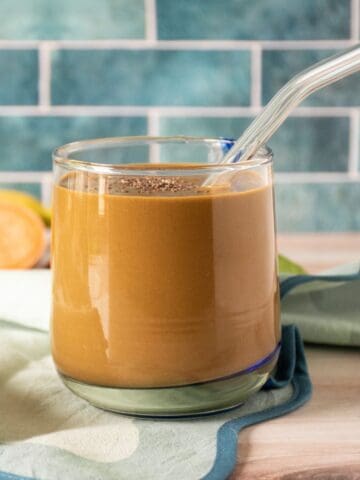Chocolate smoothie in a glass, with a clear straw, sprinkled with chia seeds.