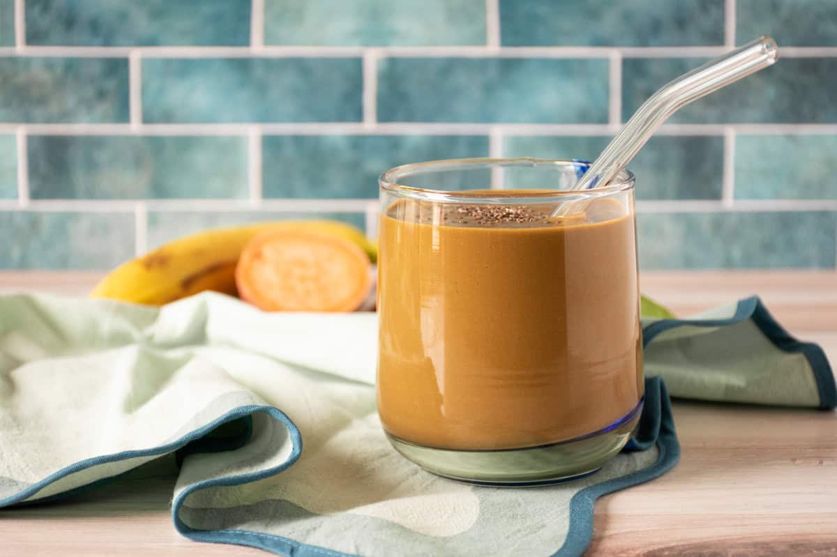 Chocolate smoothie in a glass, with a clear straw, sprinkled with chia seeds.