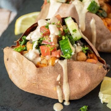 Sweet potato, stuffed with chickpeas and cucumber salad, and drizzled with tahini dressing.