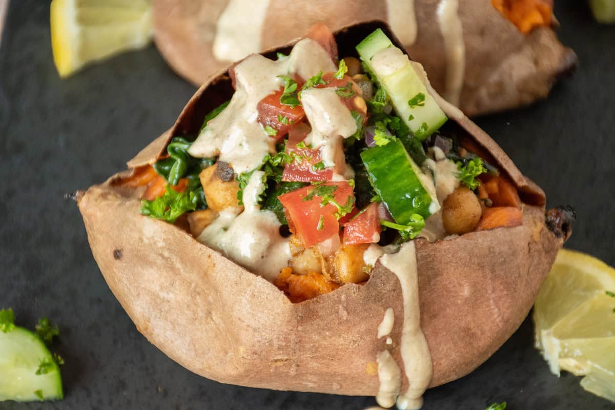 Sweet potato, stuffed with chickpeas and cucumber salad, and drizzled with tahini dressing.