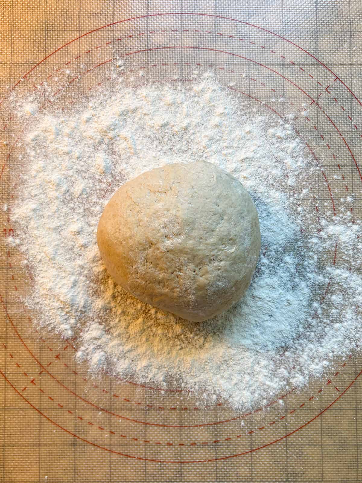 Ball of raw dough on a floured surface.