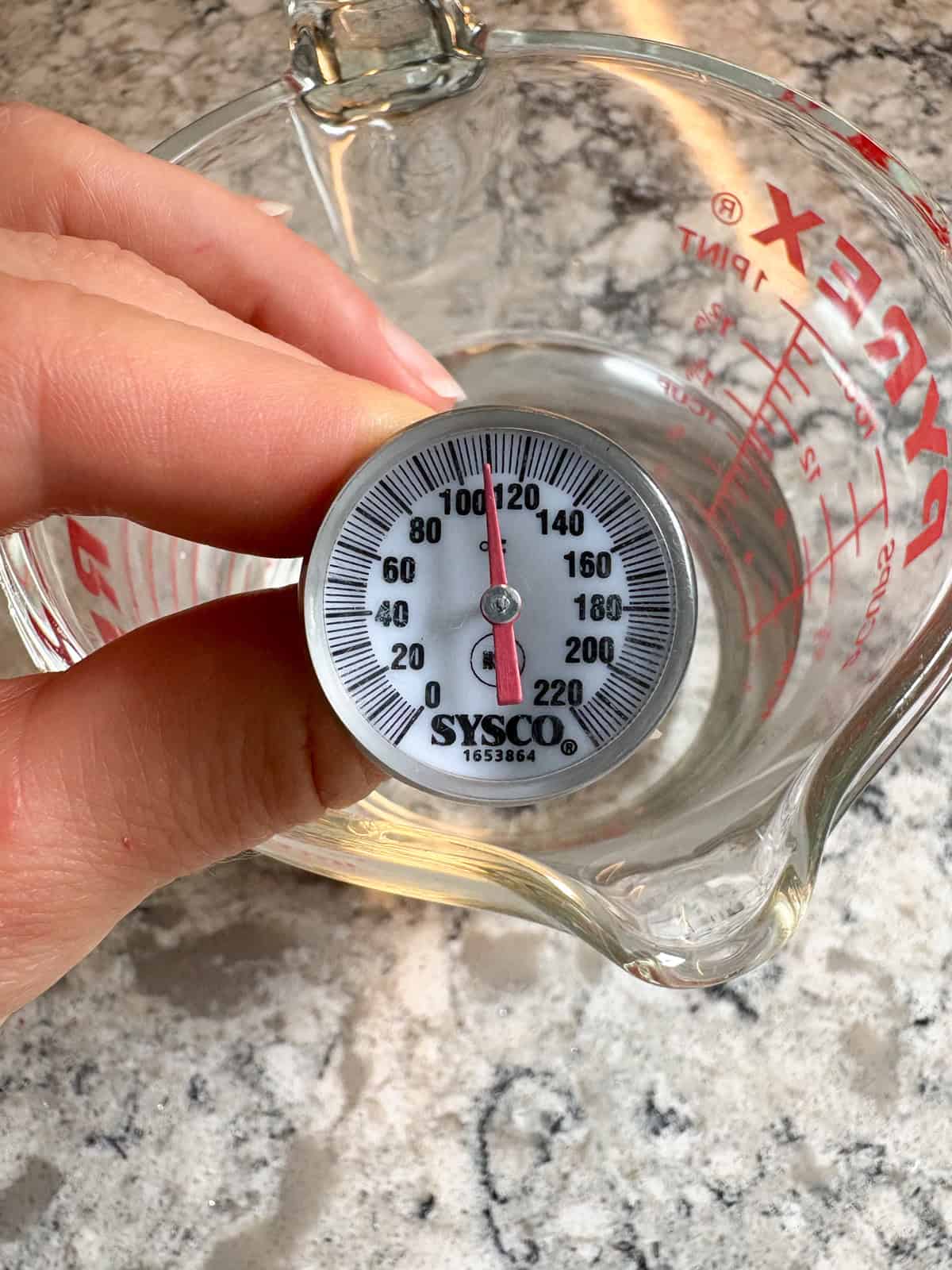 A food thermometer in water reading 110 degrees Fahrenheit.