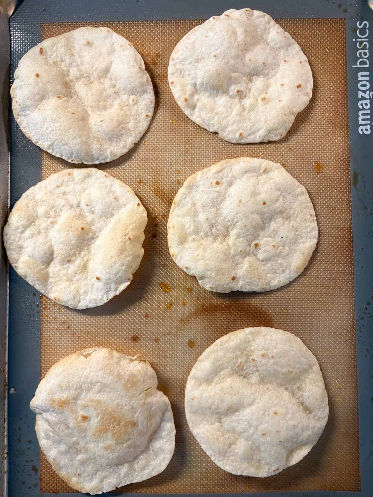 Baked tostada shells on a baking sheet.