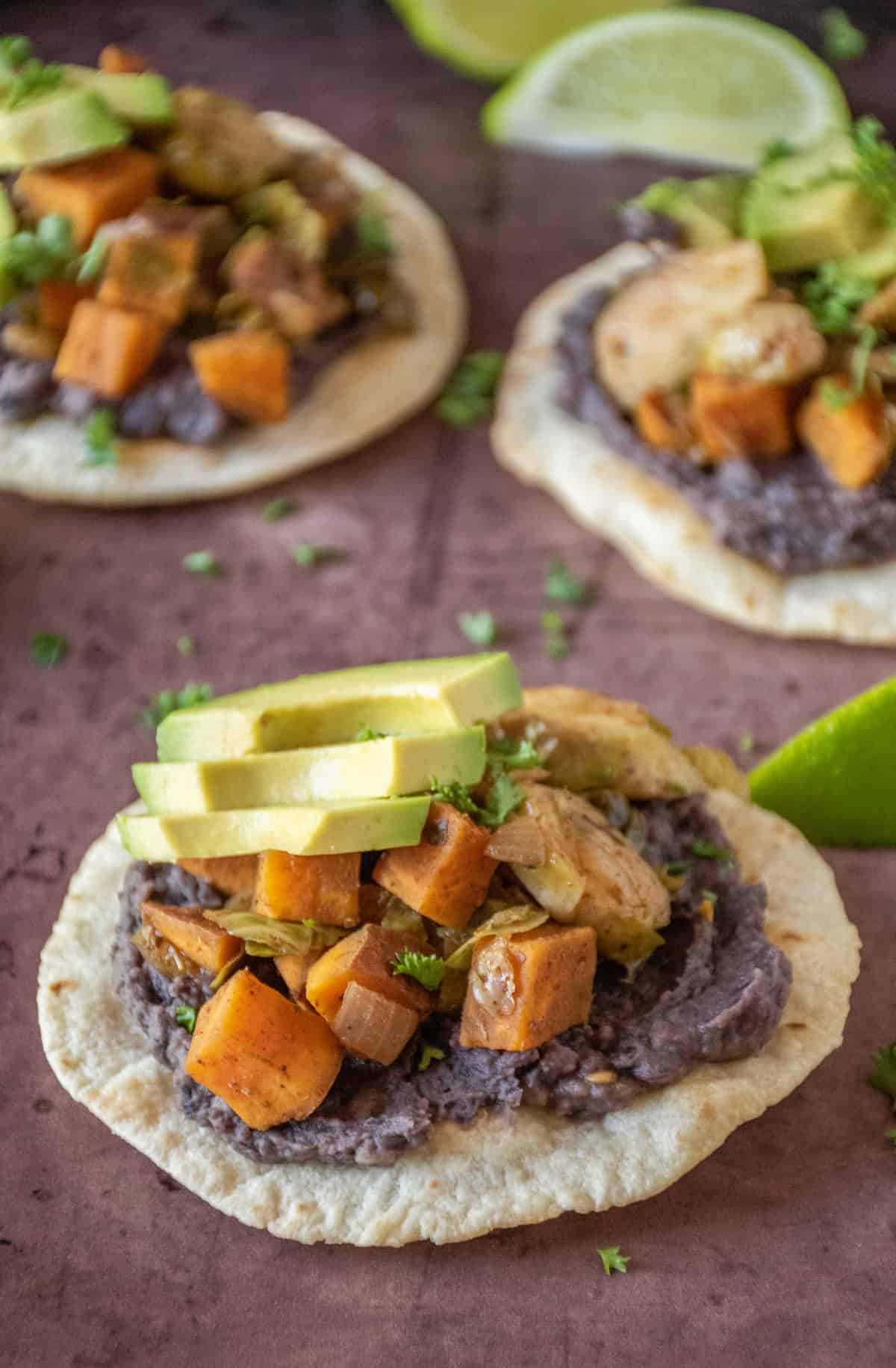 Tostada, with black bean puree and sautéed sweet potatoes and Brussels sprouts, garnished with avocado and minced parsley.