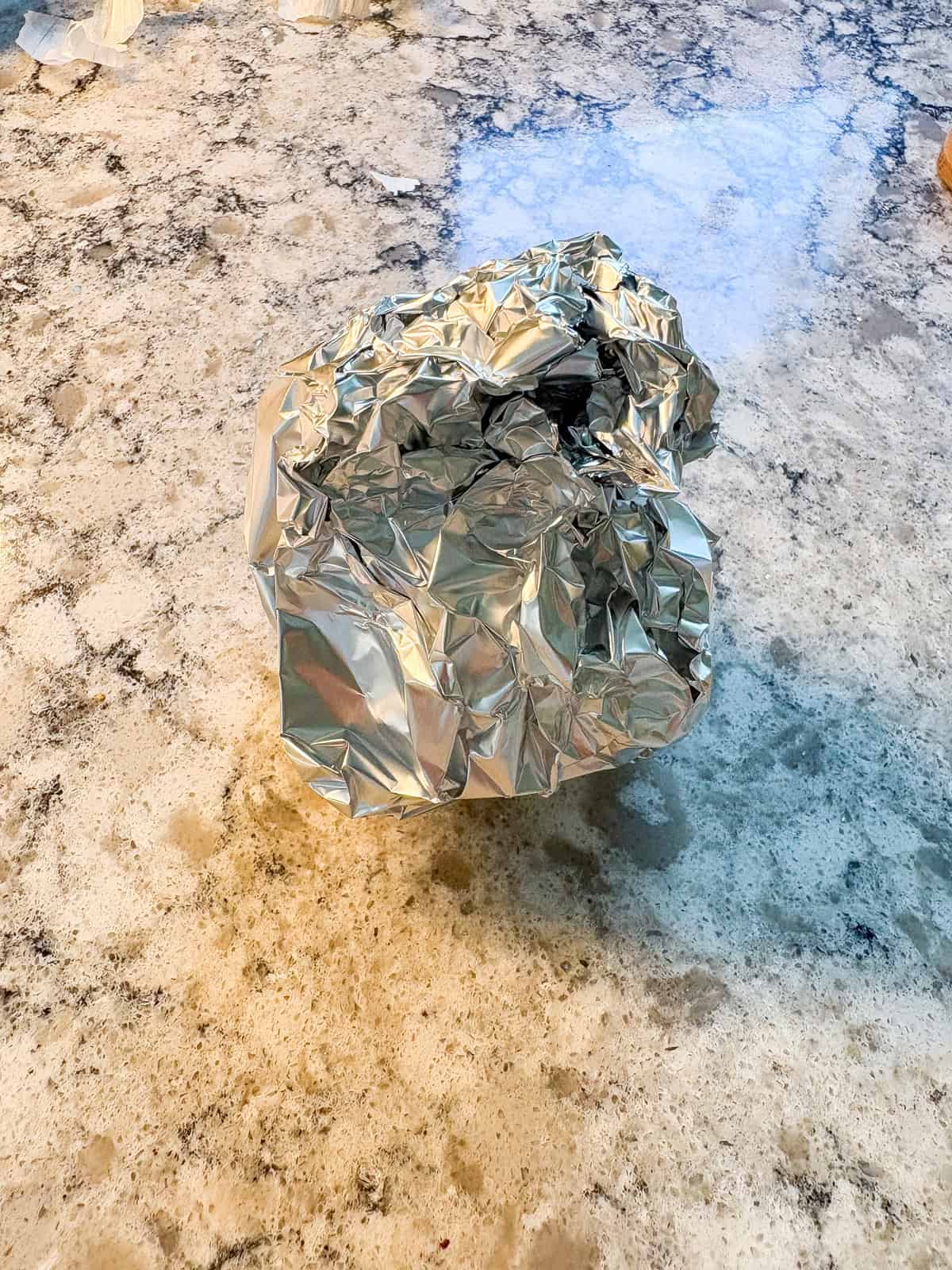 Garlic bulb wrapped in aluminum foil.