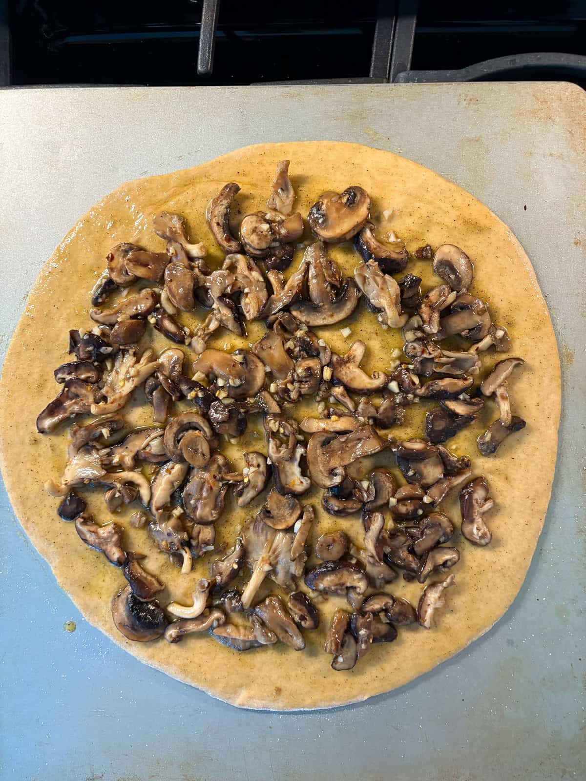 Sautéed mushrooms spread on the pizza dough.