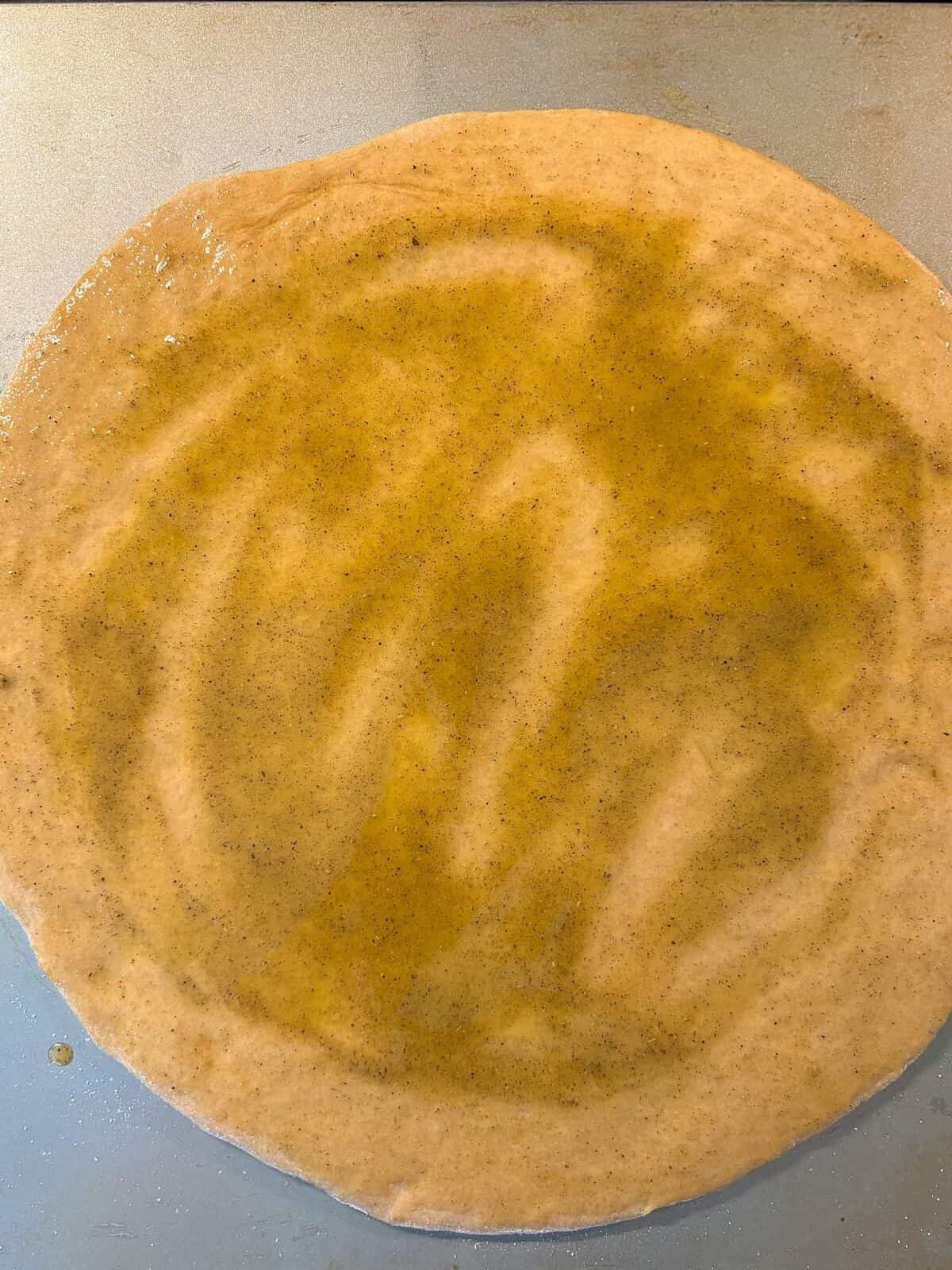 Uncooked pizza dough, rolled out to a circle, brushed with garlic oil.