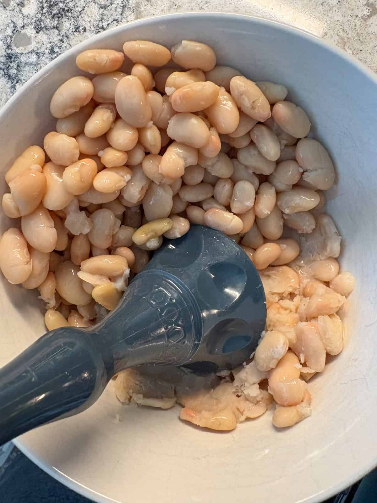 White beans in a bowl; half of them mashed.