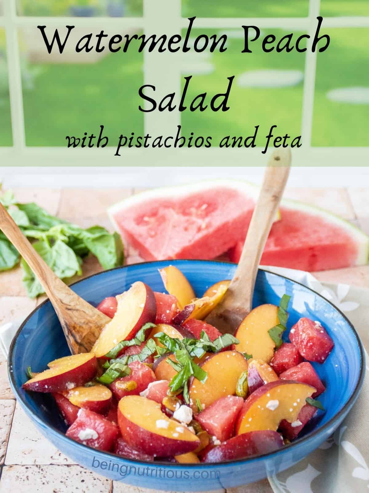 Fruit salad in a bowl with wooden serving utensils. Text overlay: Watermelon Peach Salad with pistachios and feta.