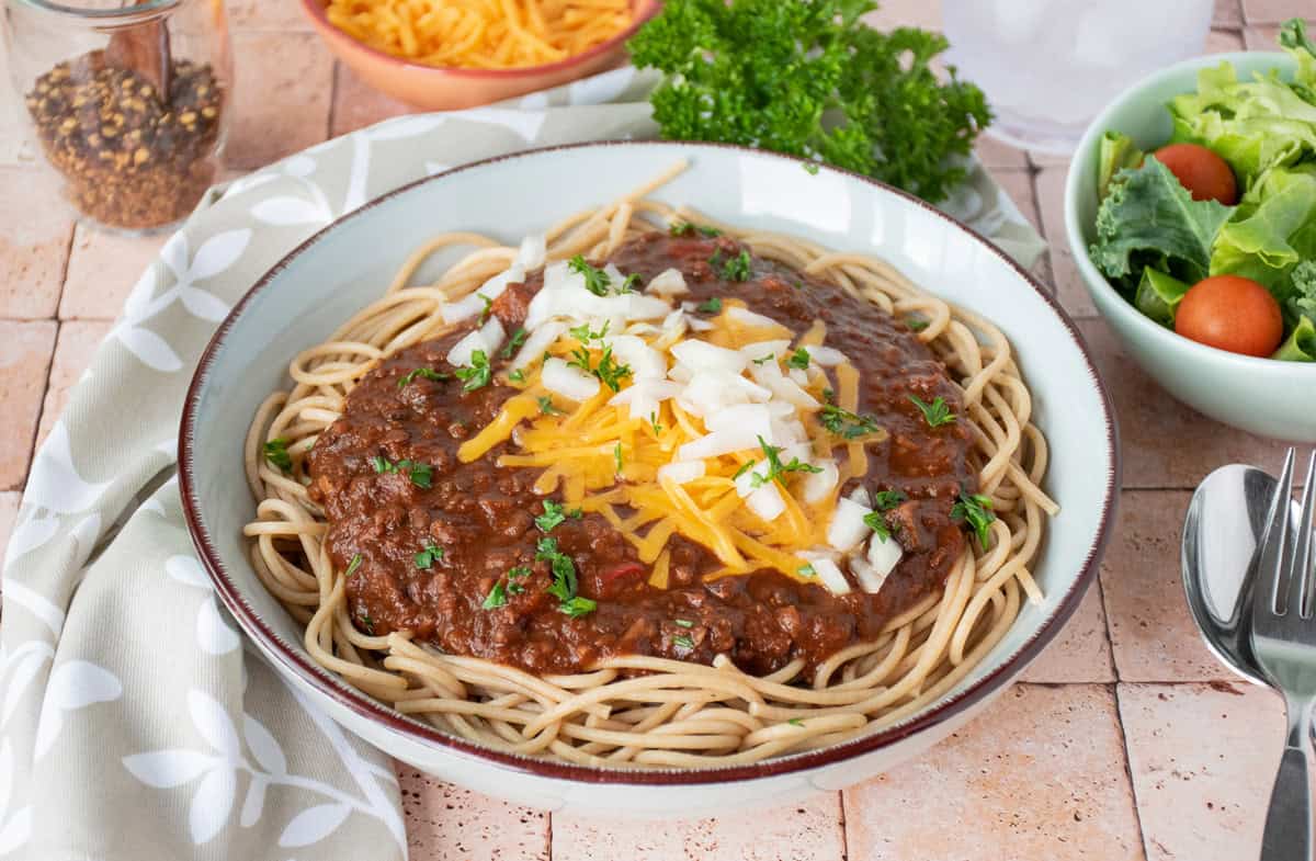 Bowl with spaghetti topped with Cincinnati chili, cheese, and onions.