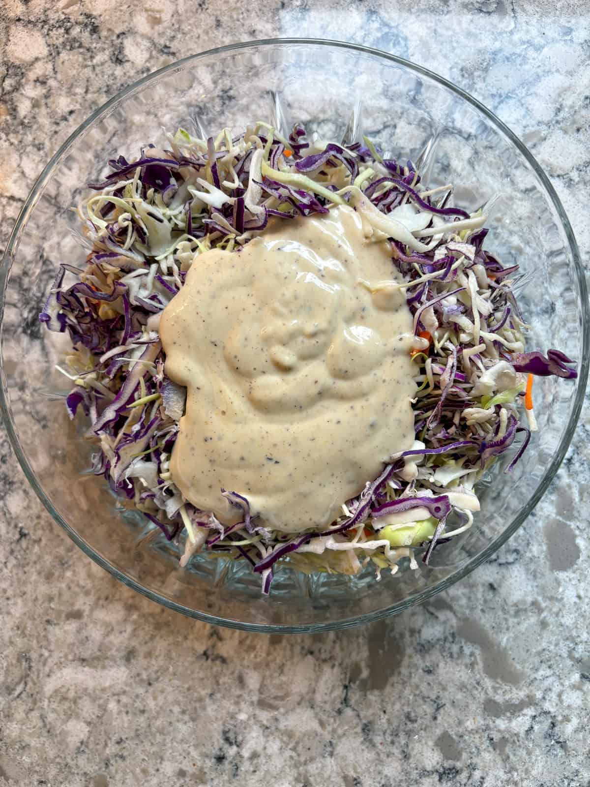 Dressing poured onto shredded cabbage mixture.