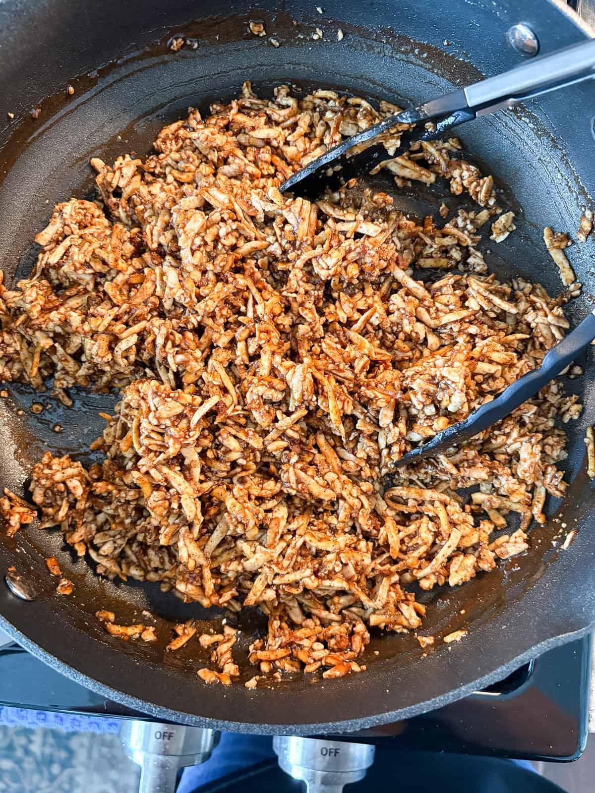 Baked shredded tofu mixed with the BBQ sauce in a pan.