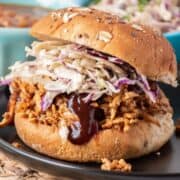 Close up of shredded BBQ tofu sandwich with coleslaw, on a hamburger bun.