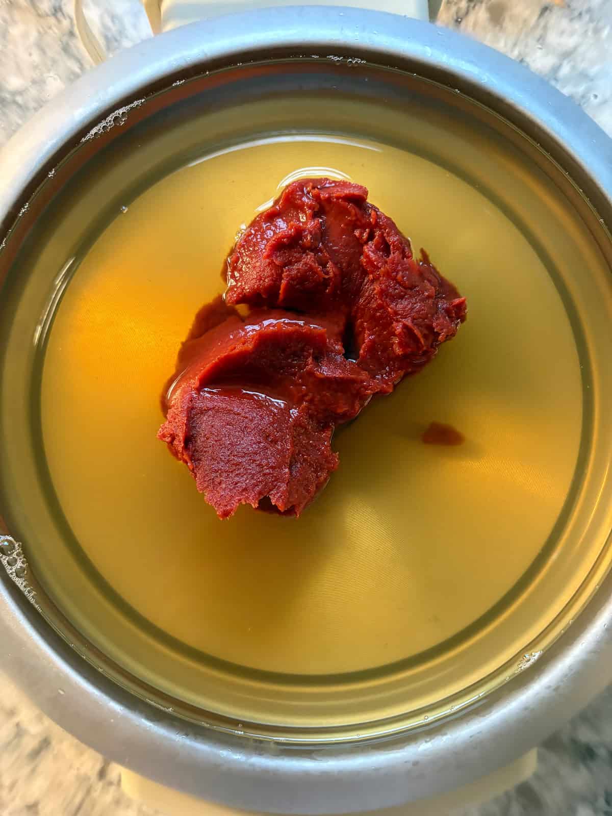 Vegetable stock and tomato paste added to the slow cooker.