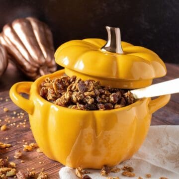A large pumpkin shaped ramekin bowl filled with granola.
