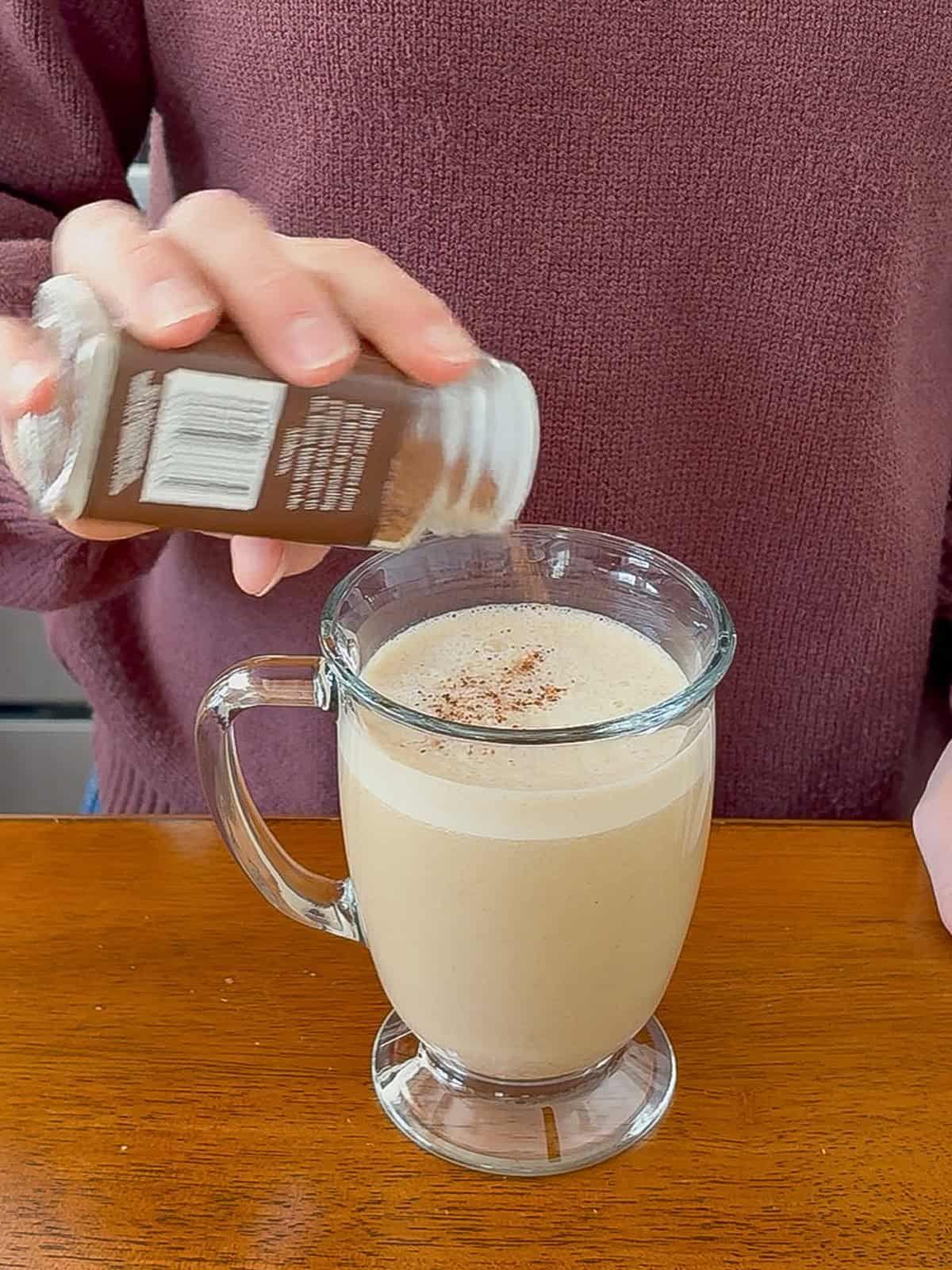 Sprinkling spices on the top of the pumpkin spice latte.