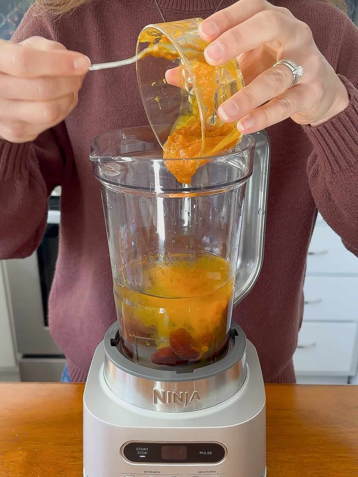 Adding pumpkin puree to the blender.